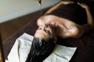 medicated oil pouring therapy on forehead for stress relief